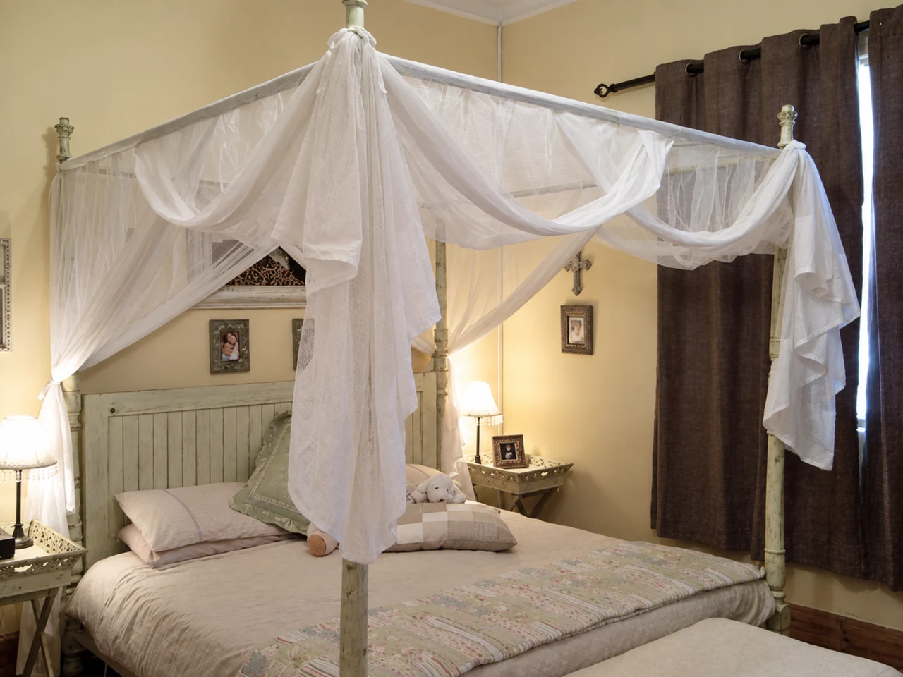 White netting gathered on a four-poster bed in a softly lit room.