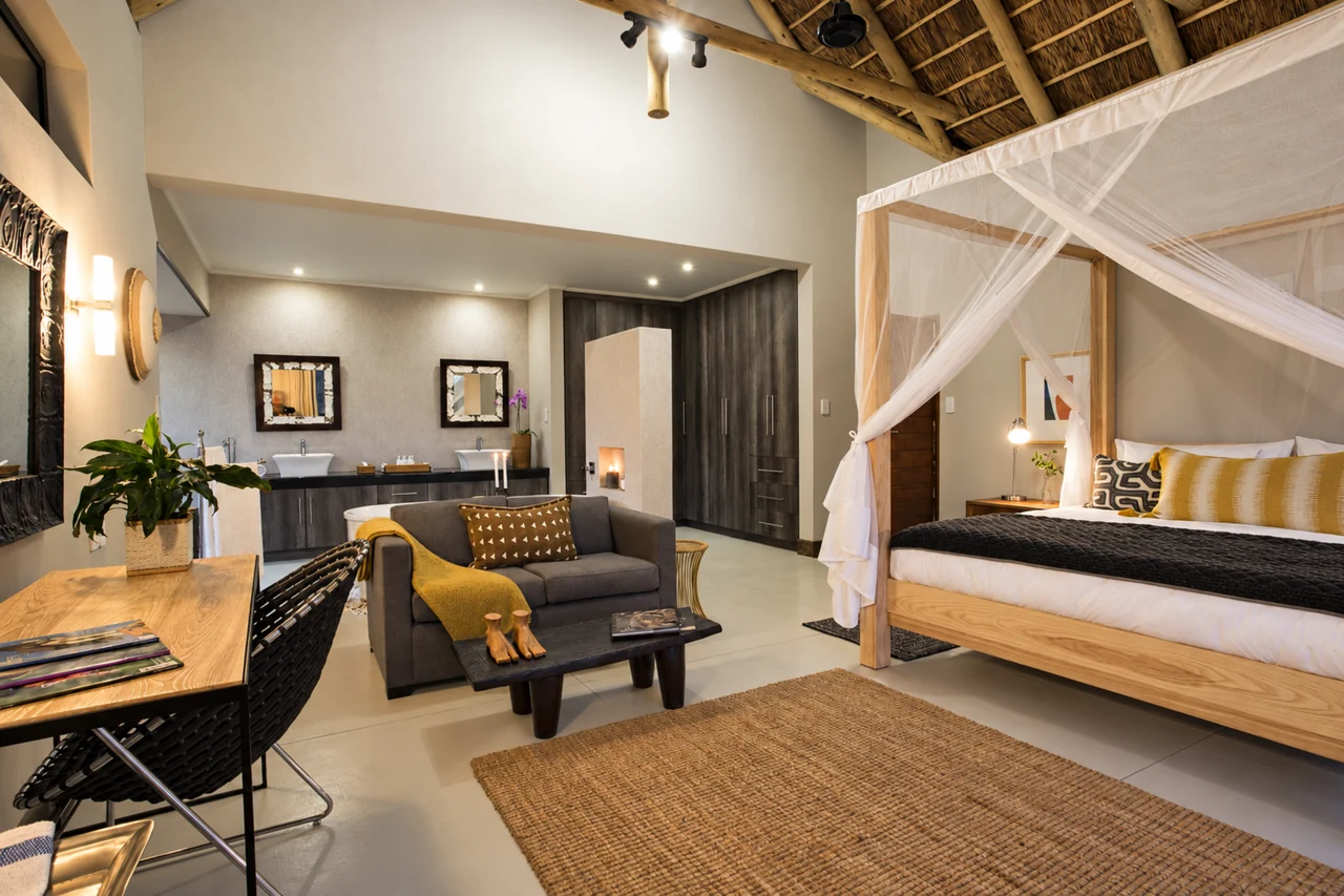 A lodge suite with white netting fitted to a four-poster bed beside the sitting area.